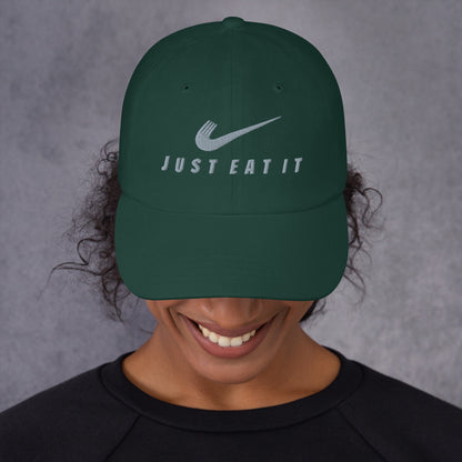 Classic spruce-colored dad hat with a Nike parody logo and "Just Eat It Dad Hat" embroidered on front by Appetite Apparel.